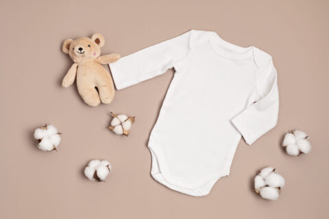 Mockup of white infant bodysuit made of organic cotton with eco friendly baby toys